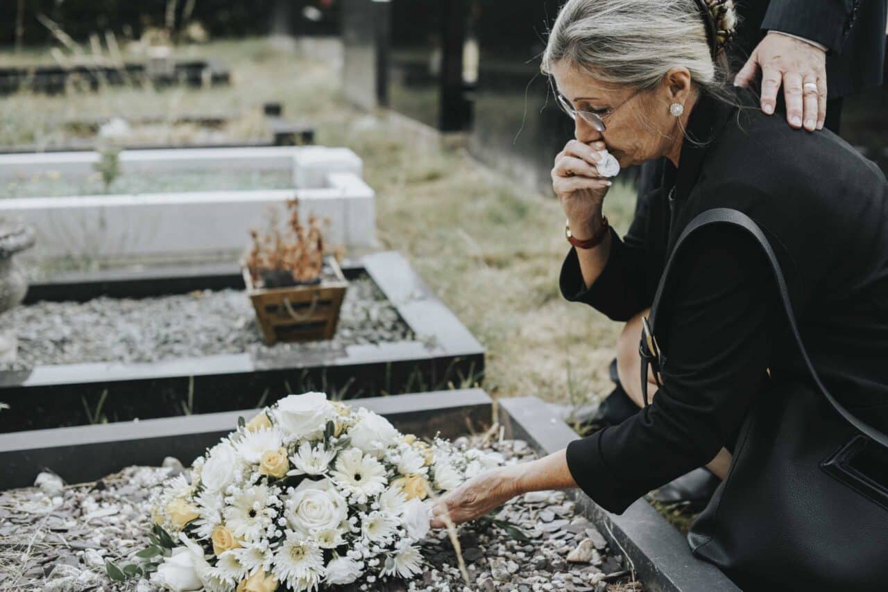 Elderly Woman Laying Flowers On A Grave