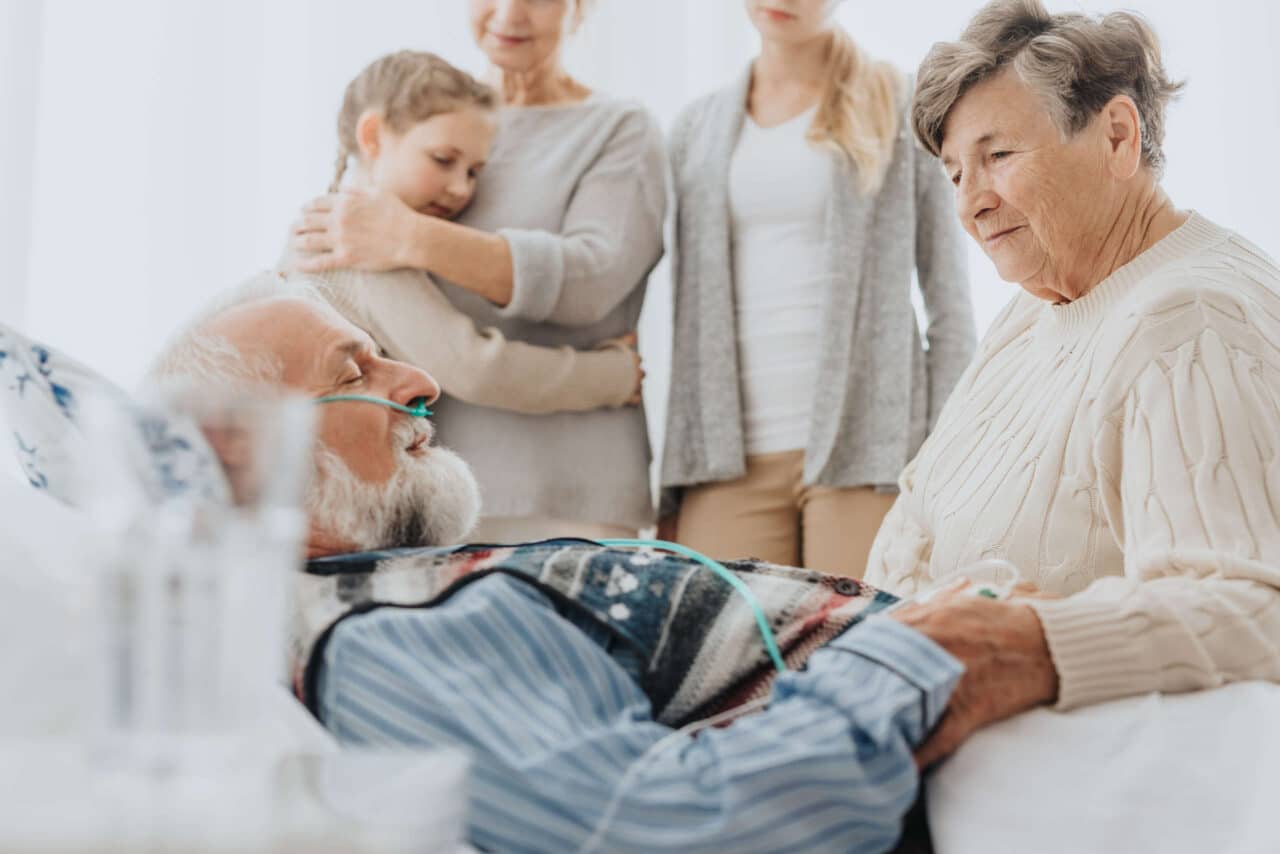 A man dying in a hospital bed surrounded by family